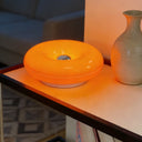 Donut LED table lamp lit in a softly styled bedroom corner