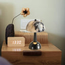 Marble mushroom lamp beside a clock on a wooden nightstand
