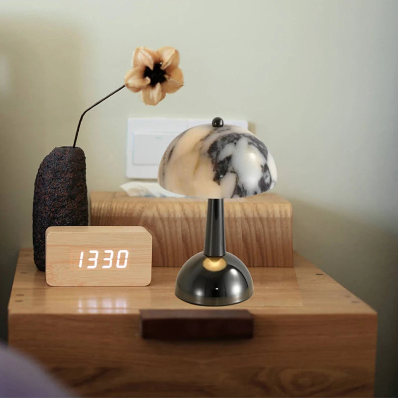 Marble mushroom lamp beside a clock on a wooden nightstand