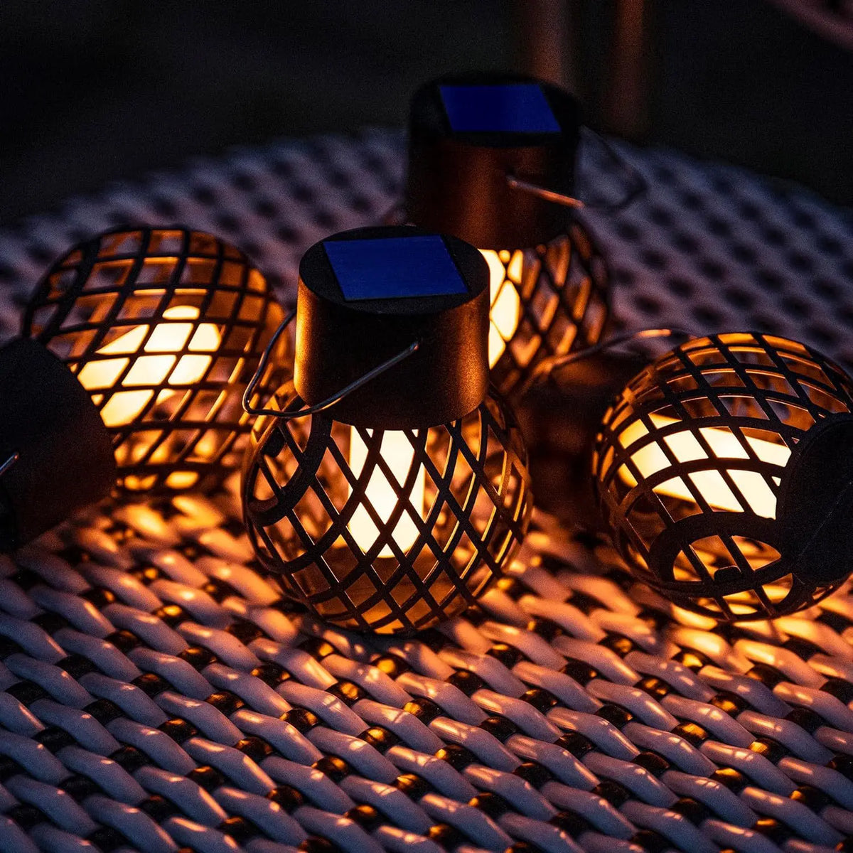 Close view of the hollow-pattern pendant lanterns showing their solar panel tops