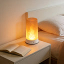 Flame table lamp on a bedside table next to an open book