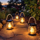 Flame-effect lanterns glowing along a garden path at dusk