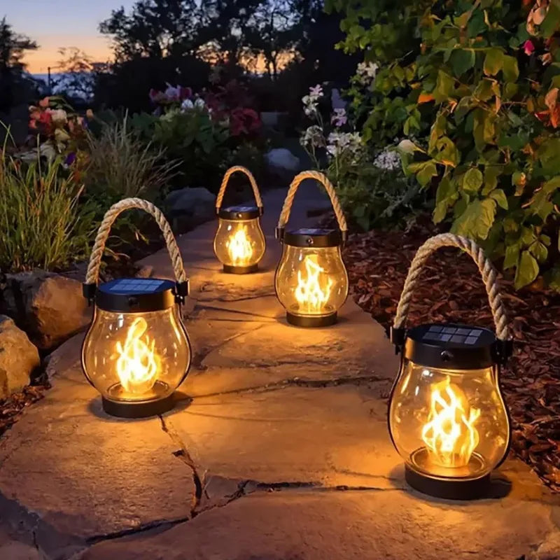Flame-effect lanterns glowing along a garden path at dusk