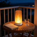 Flame table lamp on a rattan table at dusk with a glass of water