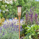 Bamboo solar torch light standing among lavender in a garden