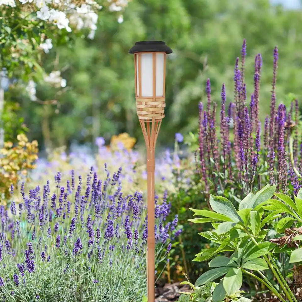 Bamboo solar torch light standing among lavender in a garden