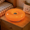 Donut LED table lamp casting warm ambient light on a shelf