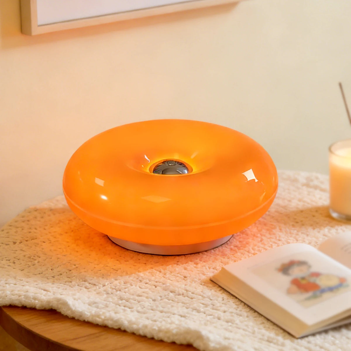 Donut LED table lamp lit on a bedside table with a reed diffuser